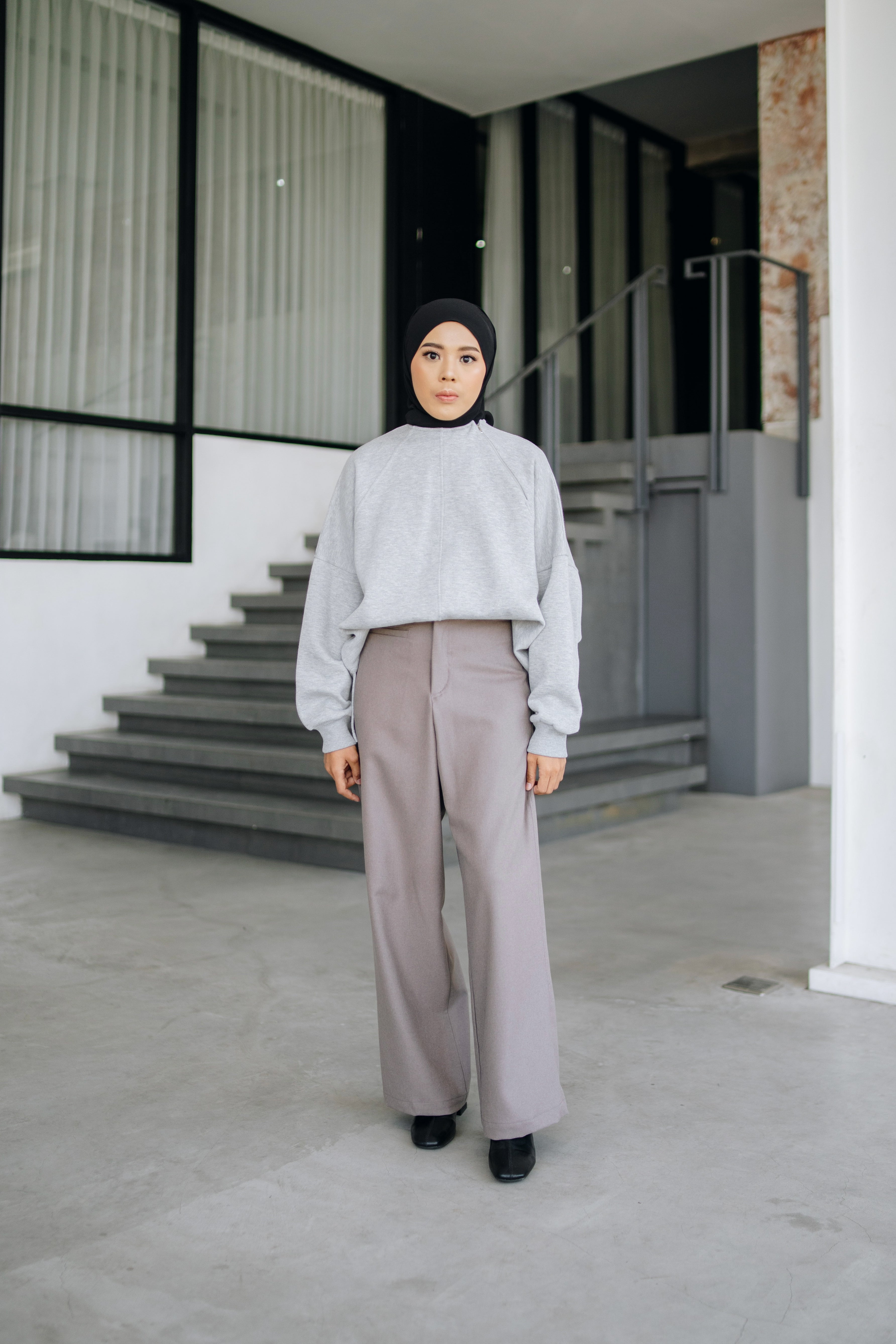 A person wearing an oversized sweater in grey color by Swifter, paired with a long skirt.