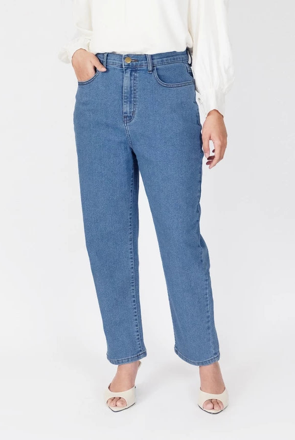 A model wearing medium-wash blue straight-leg denim pants, styled with a white long-sleeve blouse and white heeled sandals, photographed against a clean white studio background.
Seorang model yang mengenakan celana denim lurus berwarna biru dengan warna medium-wash, dipadukan dengan blus lengan panjang berwarna putih dan sandal bertumit putih, difoto dengan latar belakang studio berwarna putih bersih.