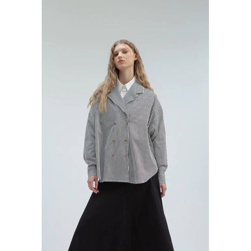 Woman wearing a checkered coat by Yestoday over a white shirt with a black skirt on a light gray background