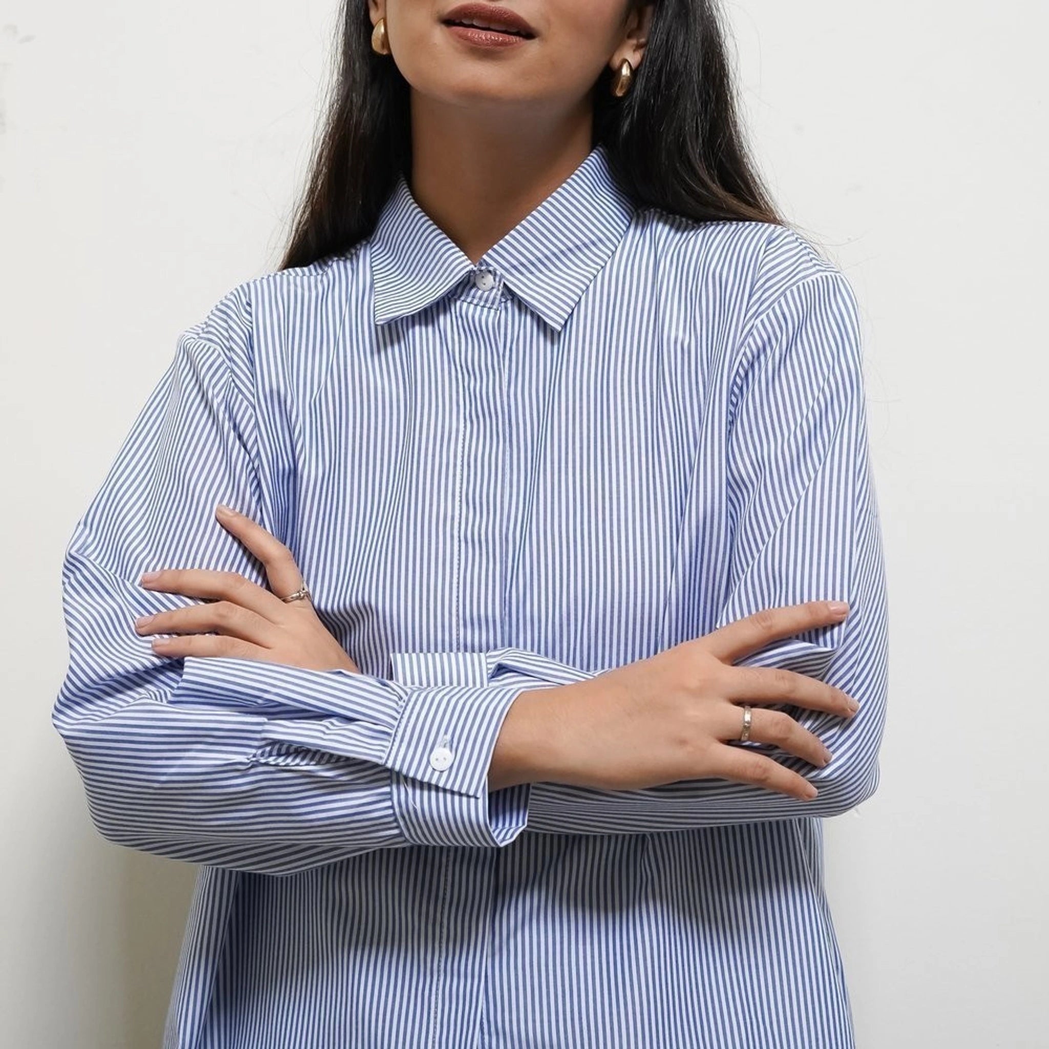 A person wearing a striped button-up shirt from BWBYAZ in blue and white, with the shirt's collar visible.