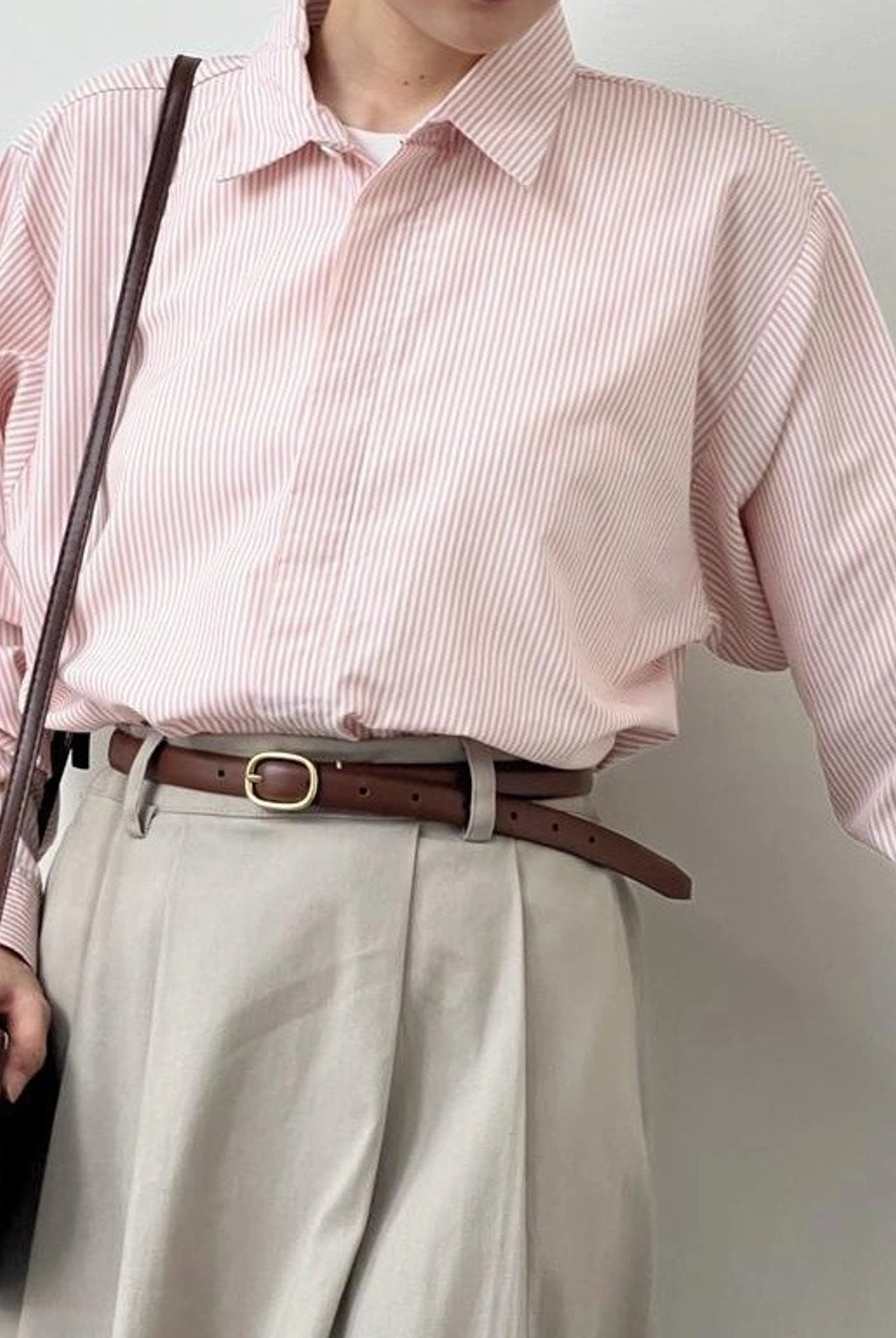 A person wearing a striped button-up shirt from BWBYAZ in pink and white, with the shirt's collar visible.