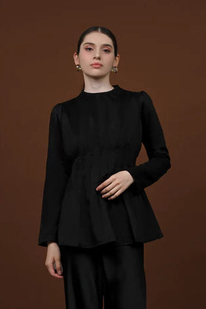 Person wearing a black long-sleeved soft lyocell top designed with pleats, a fitted waist, and puffy shoulders.