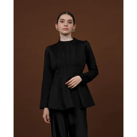 Person wearing a black long-sleeved soft lyocell top designed with pleats, a fitted waist, and puffy shoulders.