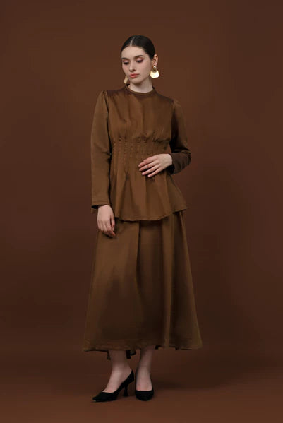 Woman wearing a brown long-sleeve soft lyocell top designed with pleats, a fitted waist, and puffy shoulders.