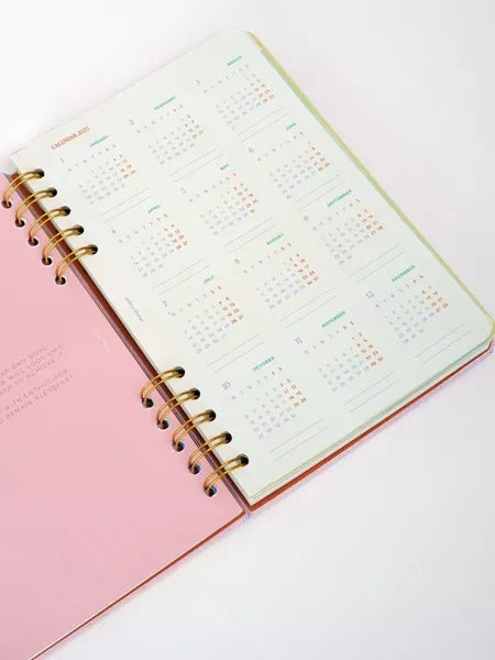 Pink planner with a gold spiral binding on a white background