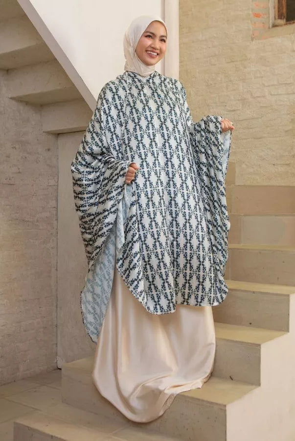 Woman wearing a patterned cream-colored prayer set by Lozy Hijab on a staircase