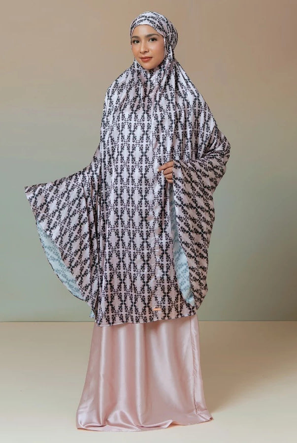 Woman wearing a patterned rose-colored prayer set by Lozy Hijab against a plain background