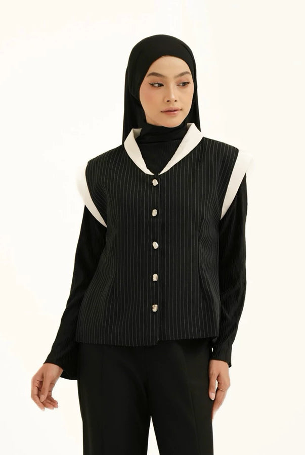 Person wearing a black vest with white accents by Tunique over black shirt on a white background