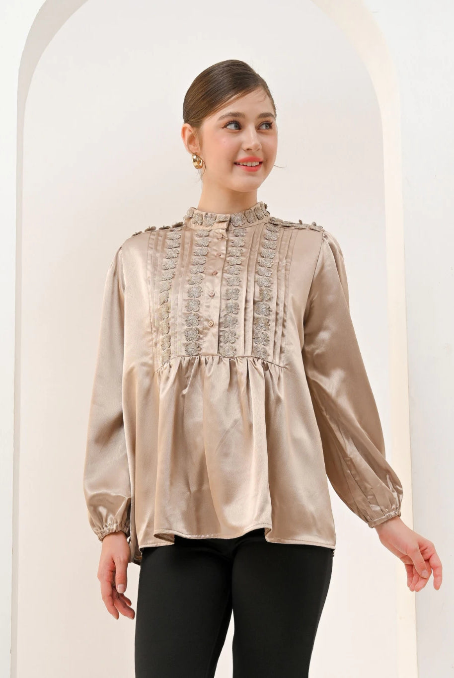 A woman wearing a brown Valca Blouse by Kasa Heritage with long sleeves and a round neckline, made of silk, with a visible textured pattern.