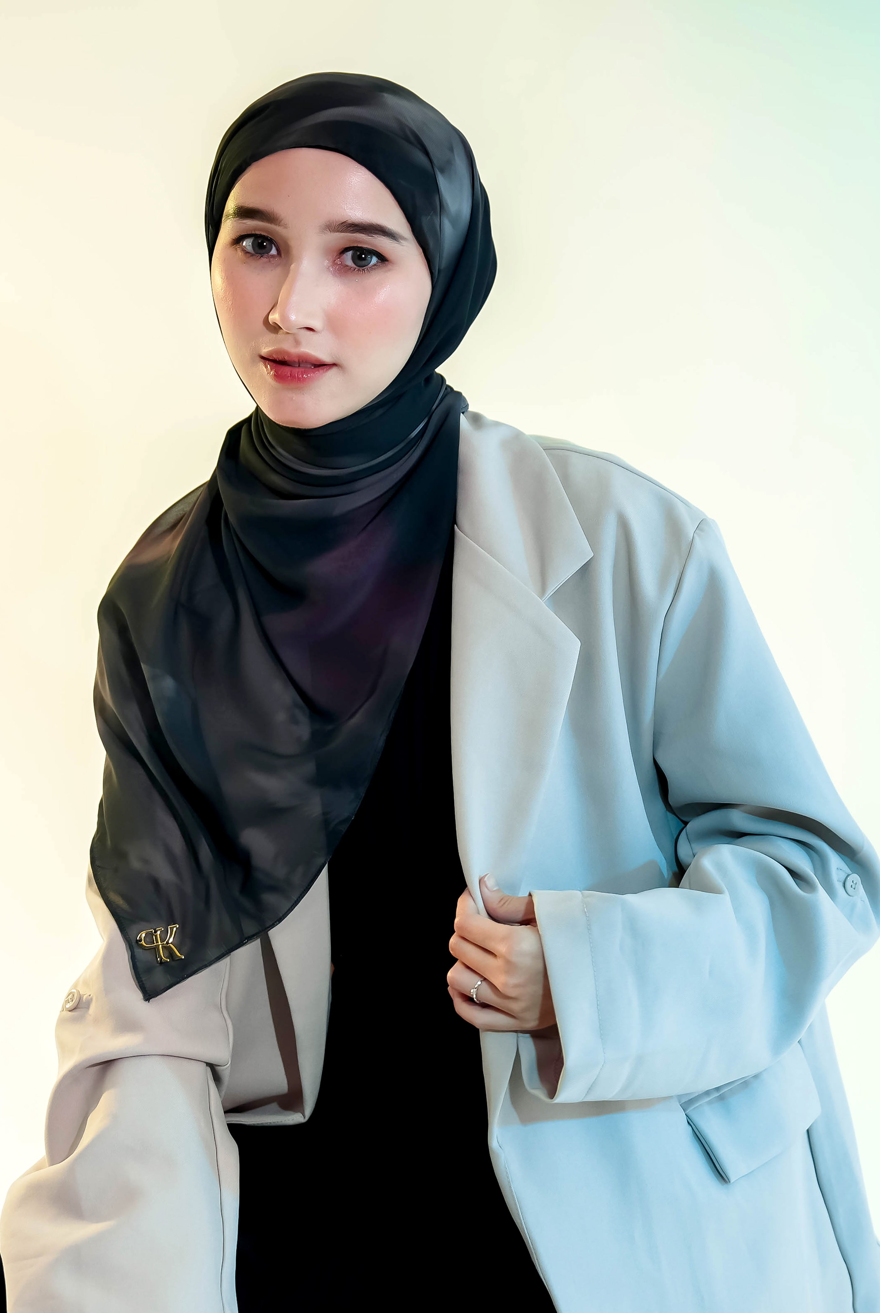 Woman wearing a black pashmina hijab by Puru Kambera and light blue blazer against a white background