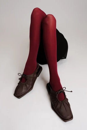Red tights worn with brown flat shoes by Cekhas on a white background