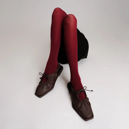 Red tights worn with brown flat shoes by Cekhas on a white background