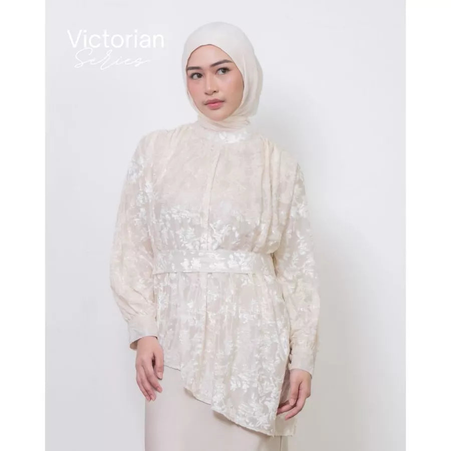 Woman wearing a white lace tunic by Atala Scarves with a plain background.
Wanita mengenakan tunik renda putih dari Atala Scarves dengan latar belakang polos.