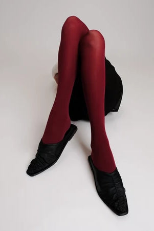 Red tights and black Vonee Mules flat shoes by Cekhas on a white background