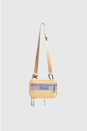 Small yellow crossbody bag with a strap from Muhajir Project on a light gray background