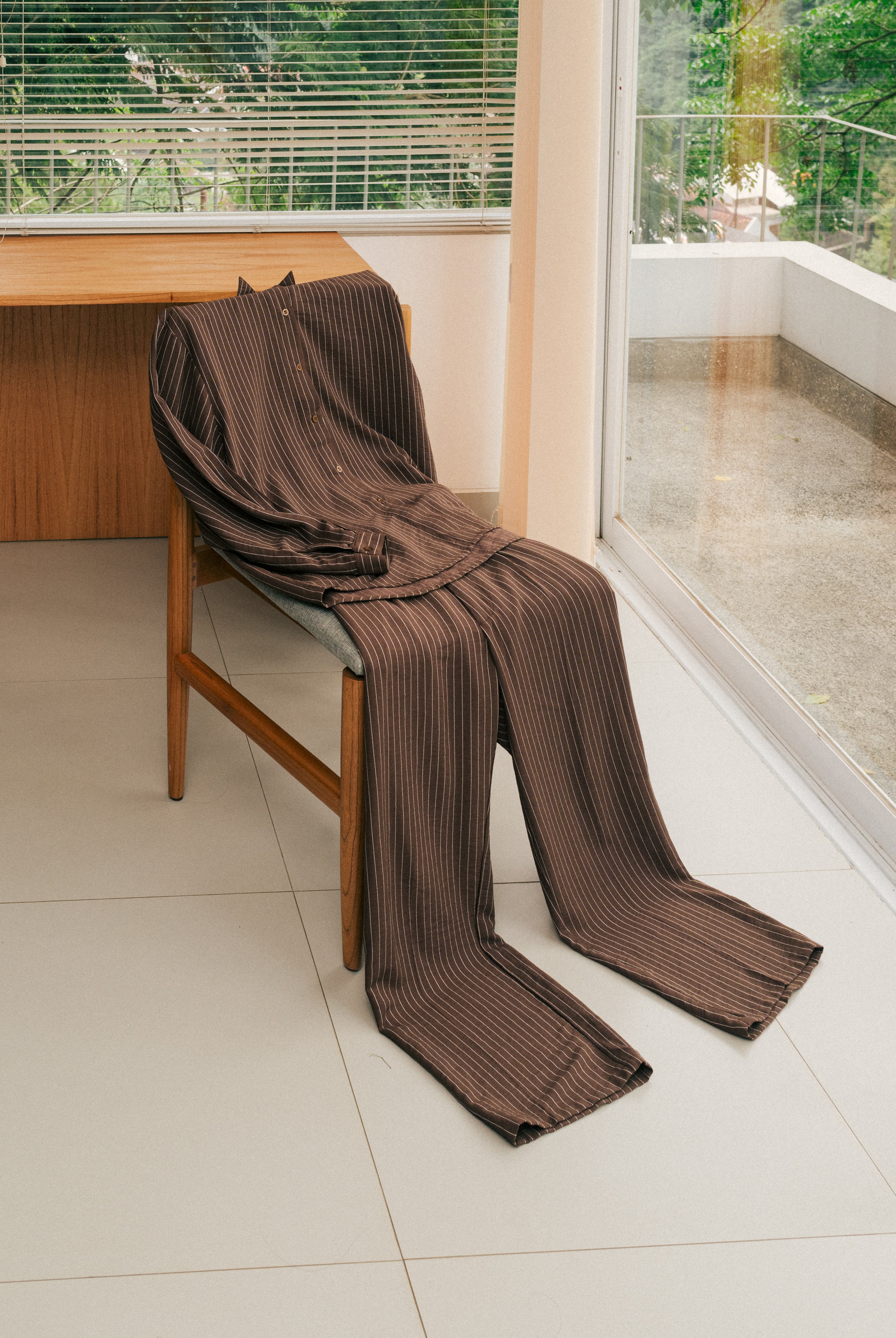 Brown striped shirt and pants from Atala Scarves draped over a chair in a room with a desk and window.