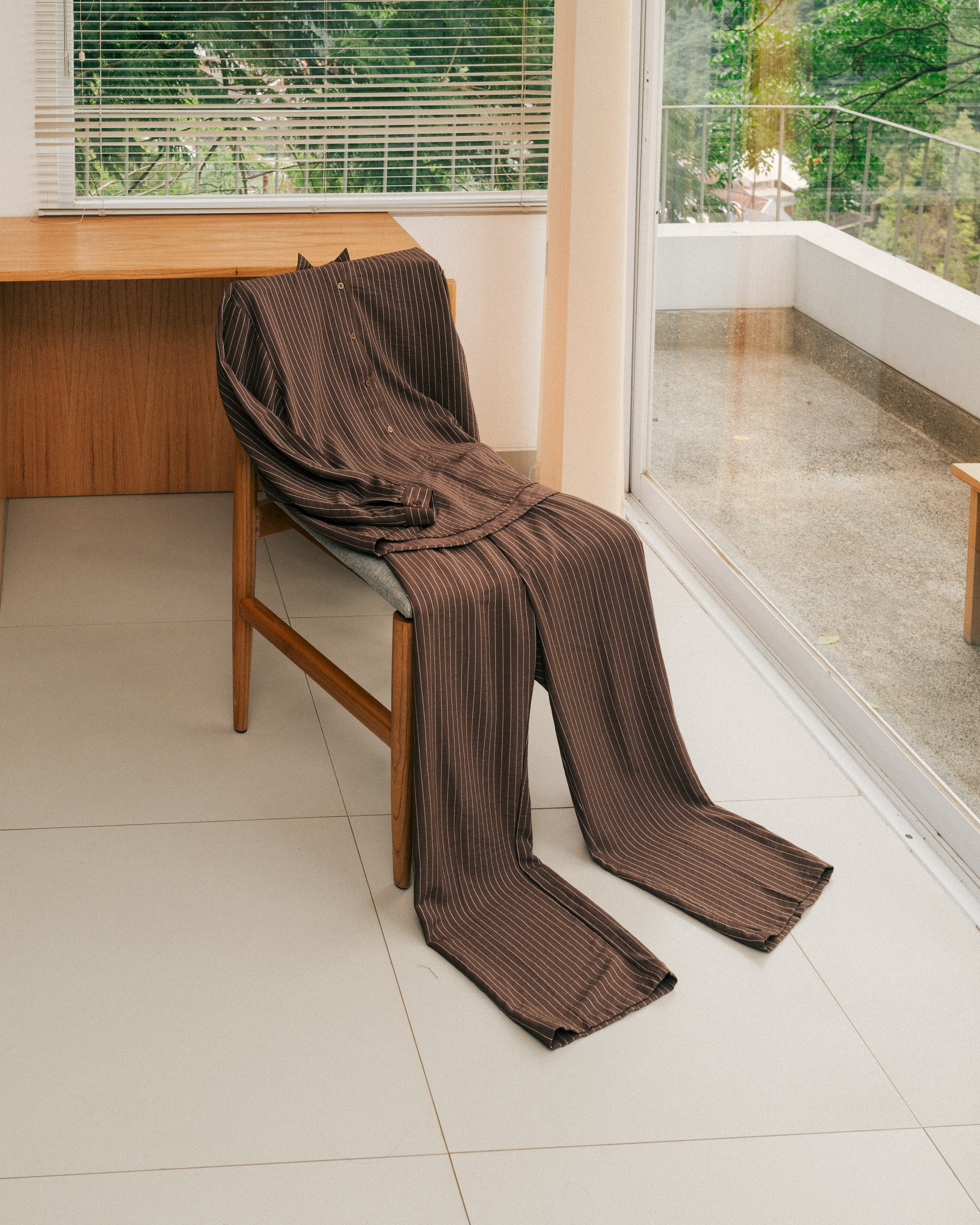 Brown striped shirt and pants from Atala Scarves draped over a chair in a room with a desk and window.