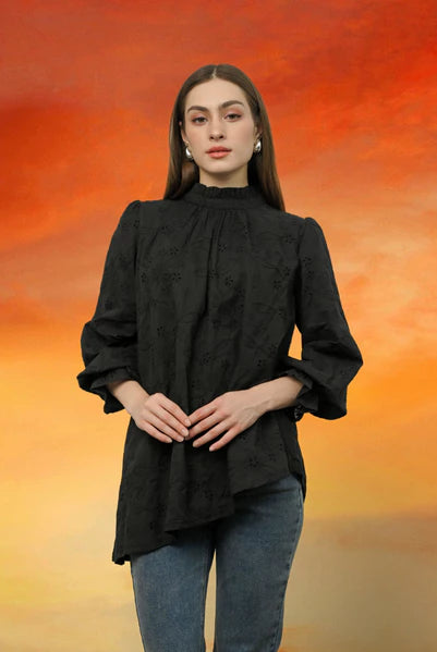 Woman wearing a black blouse by Kasa Heritage with a blurred orange and yellow background