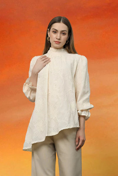 Woman wearing a ivory-colored blouse with ruffled sleeves by Kasa Heritage against an orange gradient background