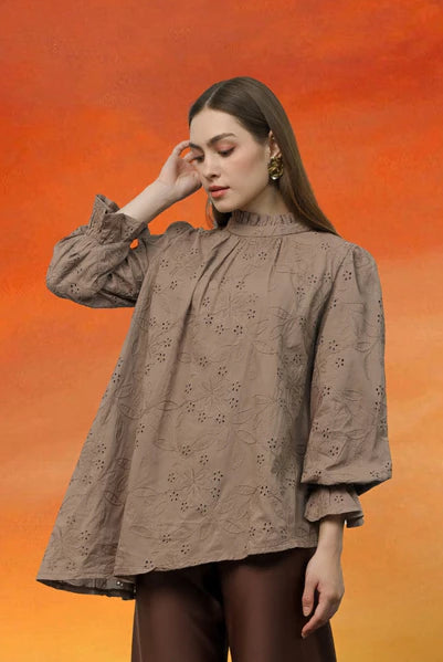 Woman wearing a brown blouse with floral details by Kasa Heritage against an orange background