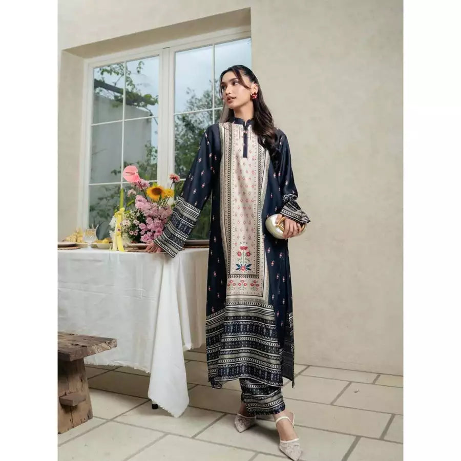 Woman in charcoal color patterned traditional outfit by Haidee Orlin standing in a room with a table and flowers.
