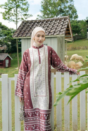Woman in a patterned set of tunic and pants from Haidee Orlin standing by a white picket fence with a garden and wooden shed in the background.
