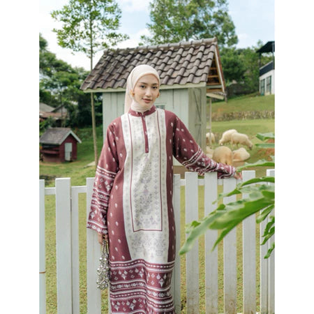 Woman in a patterned set of tunic and pants from Haidee Orlin standing by a white picket fence with a garden and wooden shed in the background.