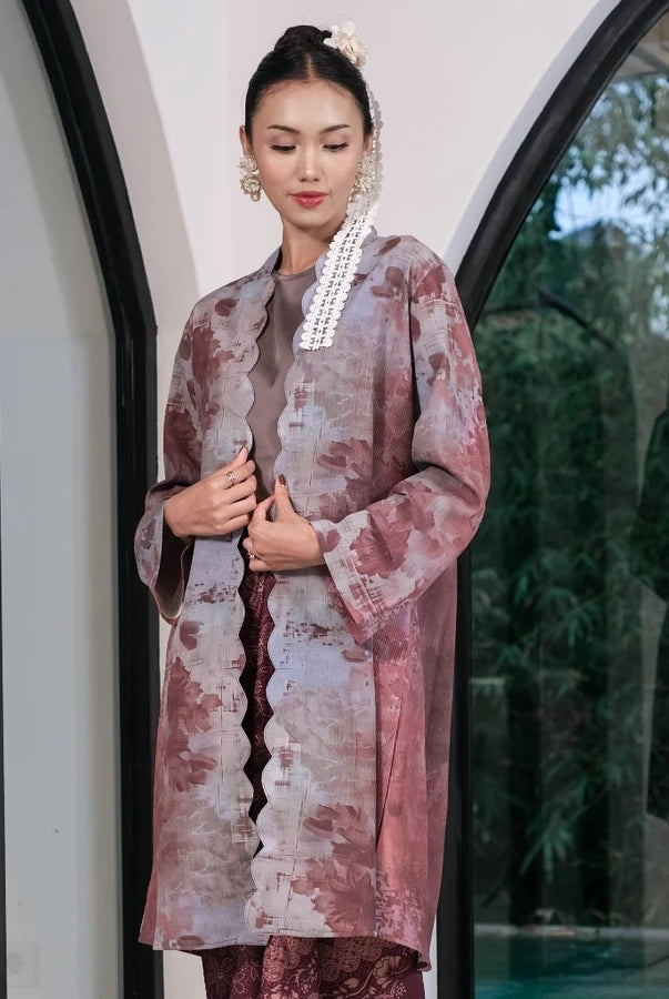 Woman in a traditional outfit by Holy Peony standing in front of a glass door with a blurred outdoor background