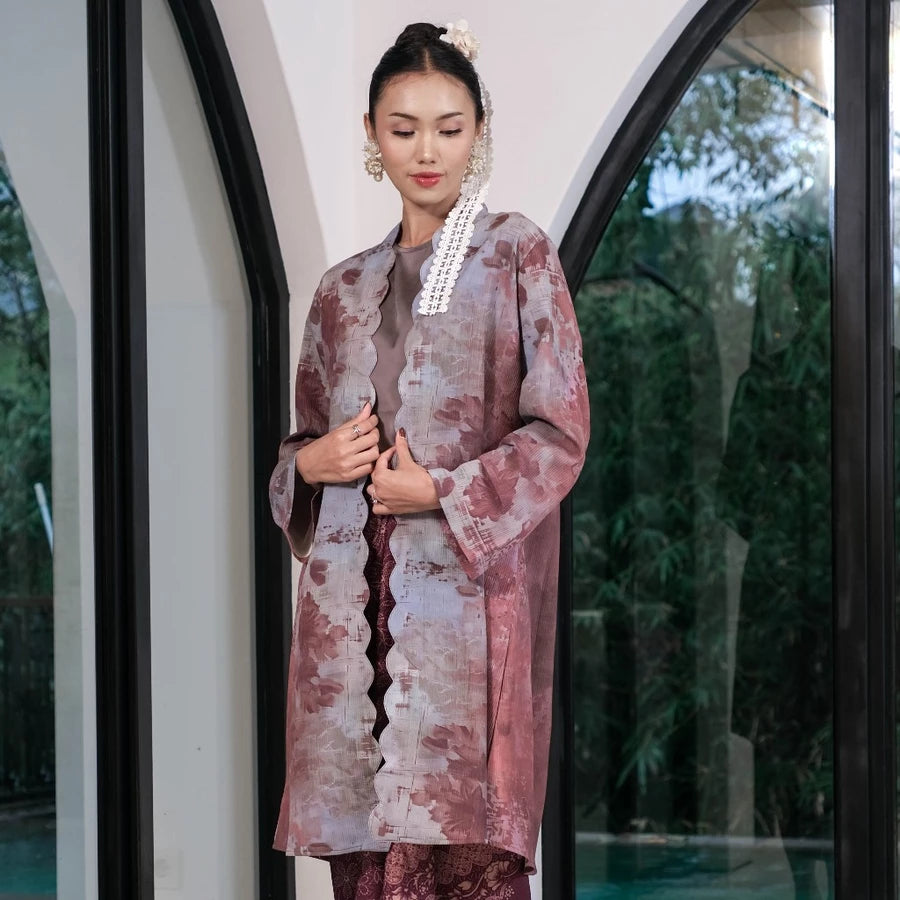 Woman in a traditional outfit by Holy Peony standing in front of a glass door with a blurred outdoor background