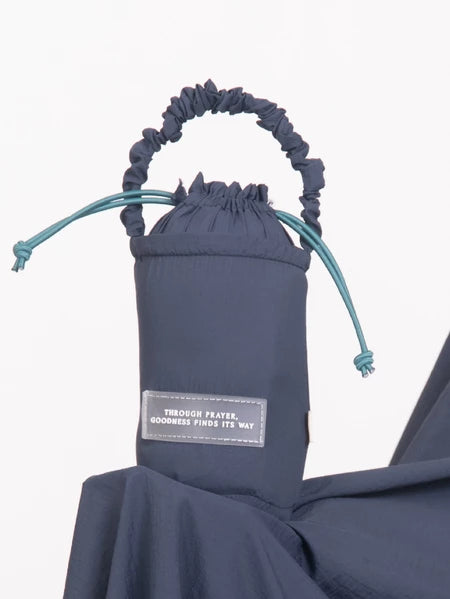 Navy blue drawstring bag from Muhajir Project with a label on a white background