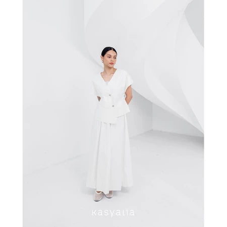 A woman wearing a white, asymmetrical button-down blouse with short sleeves and a round neckline by Kasyalia.