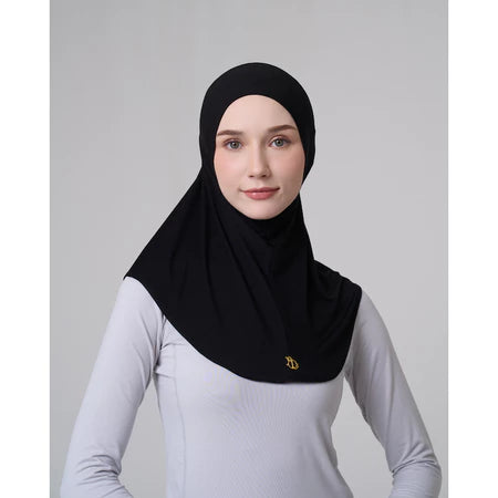 Woman wearing a black hijab sport by Inanna with a gold emblem on a gray background