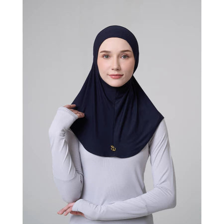 Woman wearing a navy hijab sport by Inanna and white long-sleeve shirt on a gray background