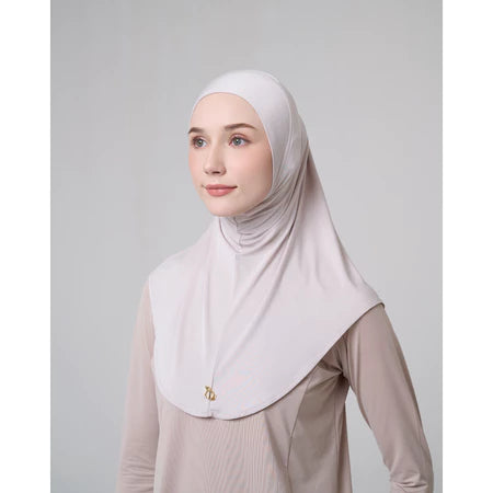 Woman wearing a light-colored hijab sport by Inanna against a plain background