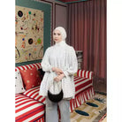 Woman standing in a room wearing white polka dot blouse by Haidee Orlin.