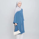 Seorang wanita menggunakan Aletha Tunic berwarna denim, sebuah tunik yang terbuat dari Cotton Bordir premium yang memberikan kenyamanan maksimal, dari Vlowy.