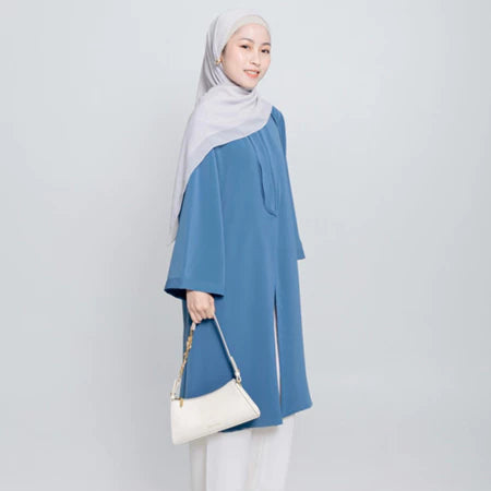 Seorang wanita menggunakan Aletha Tunic berwarna denim, sebuah tunik yang terbuat dari Cotton Bordir premium yang memberikan kenyamanan maksimal, dari Vlowy.