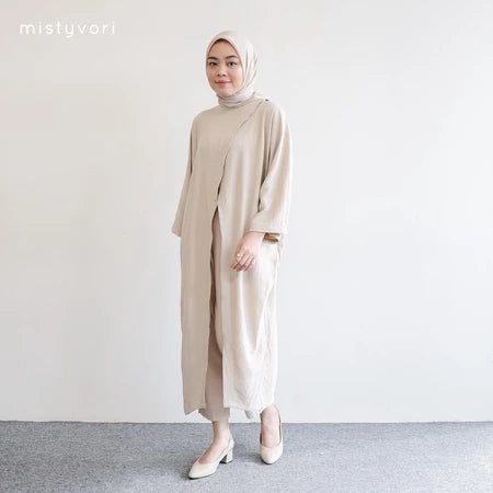 Seorang wanita memakai tunik dan hijab berwarna beige