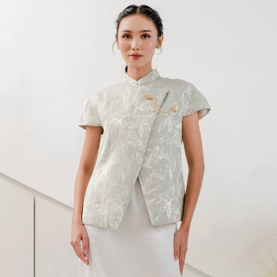Woman wearing a sage-colored traditional outfit by Holy Peony with floral patterns on a white background