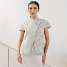 Woman wearing a sage-colored traditional outfit by Holy Peony with floral patterns on a white background