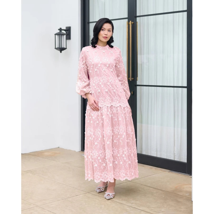 Woman in a pink floral dress by Kasa Heritage standing in front of a glass door.
