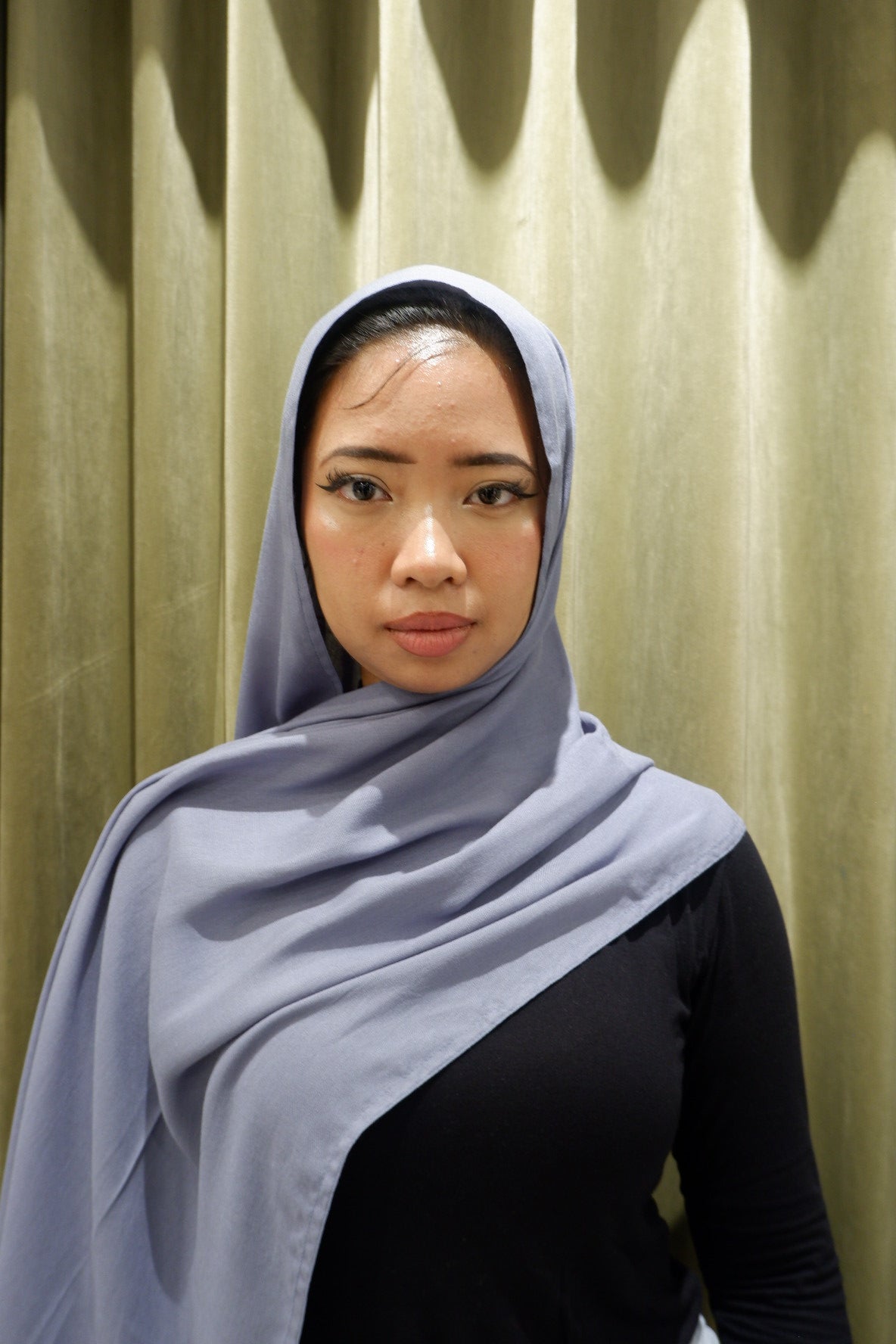 Woman wearing a denim-colored hijab pashmina viscose against a wooden background