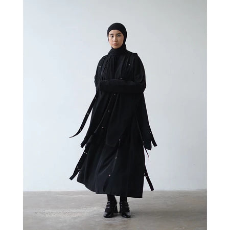 Person wearing a long black vest by Rashawl against a plain background