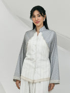 Woman wearing a white and gray women’s blouse by Studio Tui featuring a front button closure, mandarin collar, and delicate lace trim along the edges. Paired with matching bottoms for a refined and elegant look.