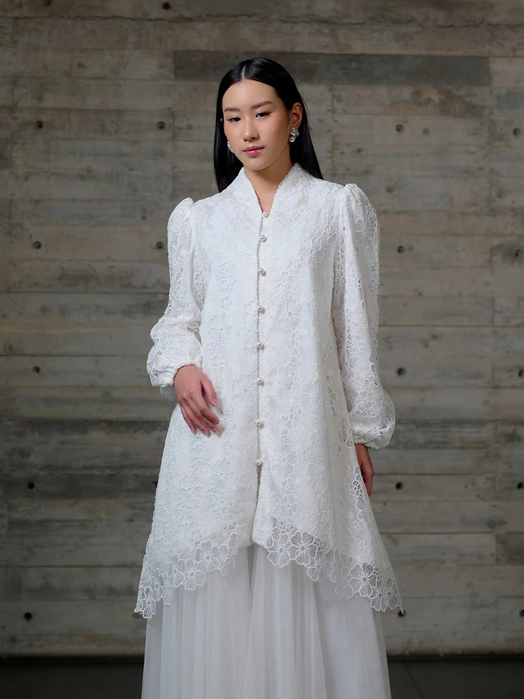 Woman wearing a white lace long blouse by Kasa Heritage against a wooden background.