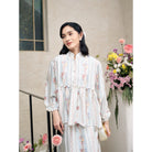 Woman in a floral outfit set by Haidee Orlin with blue accents standing outdoors with flowers in the background