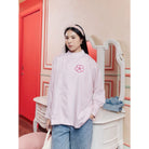 Woman wearing a light pink blouse by Haidee Orlin with a floral design in a room with red walls and white furniture.