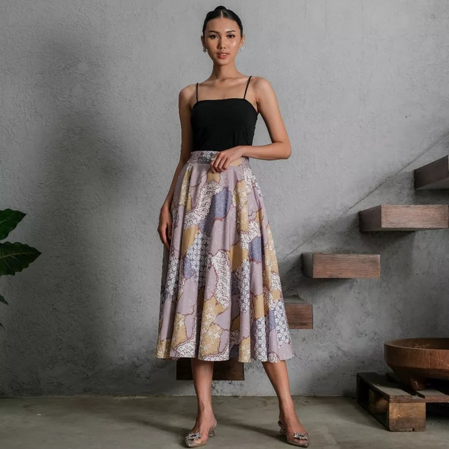 Woman wearing a black top and patterned skirt by Holy Peony standing in a modern interior setting.