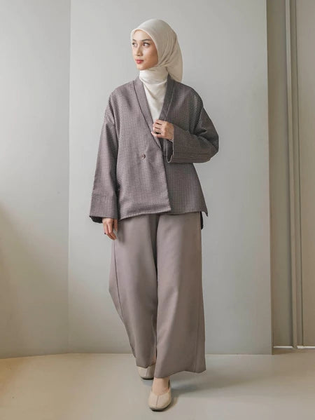 Woman wearing a latte-colored checkered blazer by Mistyvori with a hijab against a plain background