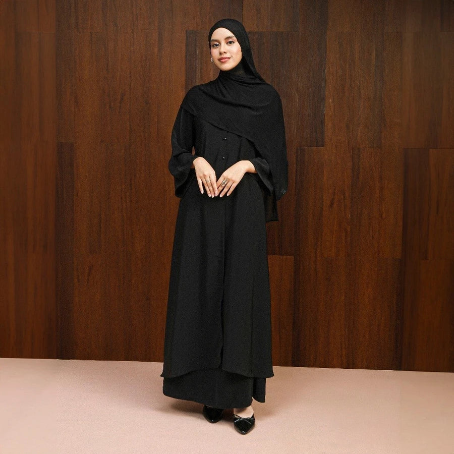 Woman wearing a black abaya dress by Lozy Hijab against a wooden background